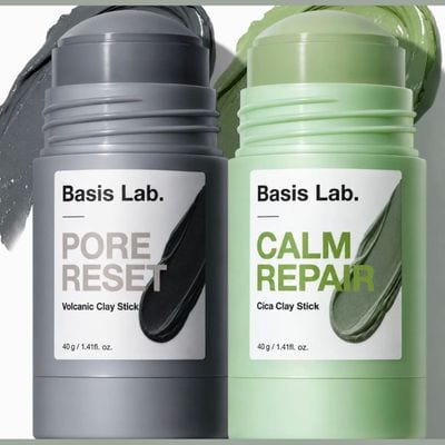 Basis Lab Pore Reset grey volcanic clay stick and Calm Repair green cica clay stick, 40 g each, with swatches of both masks behind them